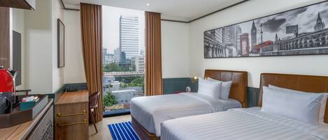 A hotel room with two beds, a desk, a chair, a window with curtains, and a cityscape view.