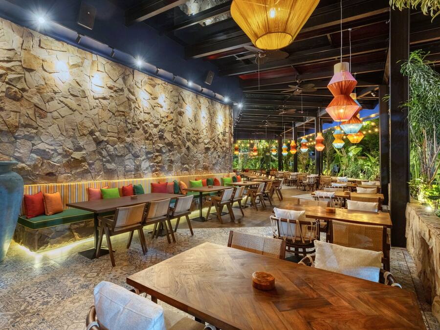 A restaurant with stone walls, wooden tables, and colorful hanging lights.