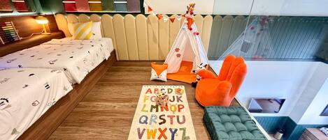 A cozy bedroom with a bed, a small tent, a chair, and a rug with alphabet letters.