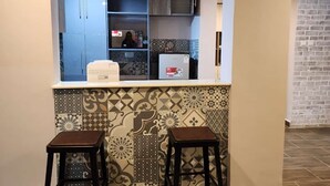 A kitchen with two stools, a refrigerator, and patterned tiles.