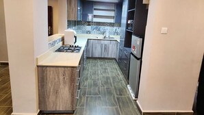 A modern kitchen with a central island, dark wood cabinets, and a tiled backsplash.