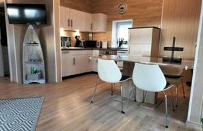Une cuisine moderne avec des meubles blancs, un four à micro-ondes et un coin repas équipé de deux chaises blanches.