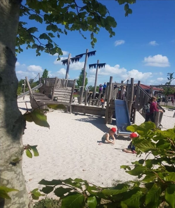 Une aire de jeux avec des structures en bois et un toboggan.