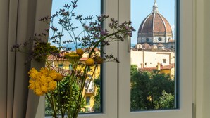 A window view of a building with a dome, through which a bouquet of flowers is visible. - Il Santo Stays (Florence)