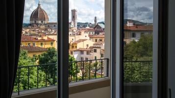 Vista da una finestra su un paesaggio urbano con architettura storica, che include una cupola imponente e torri.