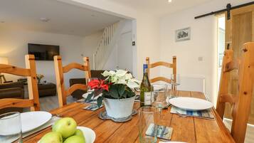 A dining table set with plates, a bowl of apples, a wine bottle, and glasses.