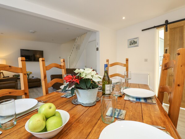A dining table set with plates, a bowl of apples, a wine bottle, and glasses.