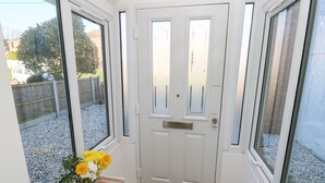 A white door with a mail slot, flanked by windows with white frames and clear glass. - 1 Star Cottages (Freshwater)