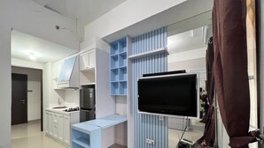 A modern kitchen with white cabinets, a blue countertop, and a built-in TV. - Transpark Juanda by Bonzela Property (Bekasi)