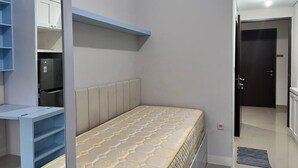 A bedroom with a bed, built-in shelving, and a wardrobe. - Transpark Juanda by Bonzela Property (Bekasi)