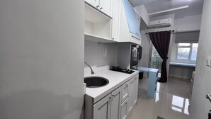 A modern kitchen with white cabinets, a black sink, and a built-in stove. - Transpark Juanda by Bonzela Property (Bekasi)