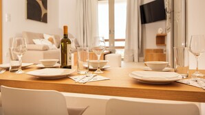 A dining table set with plates, glasses, and cutlery, with a bottle of wine and a bowl in the center.