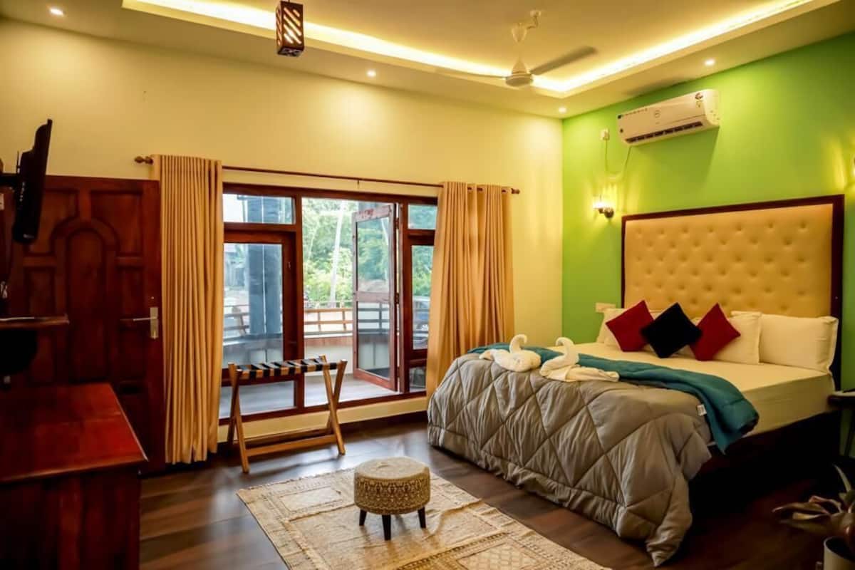 Un dormitorio con una cama grande, un escritorio de madera y vistas al exterior a través de una puerta corredera.