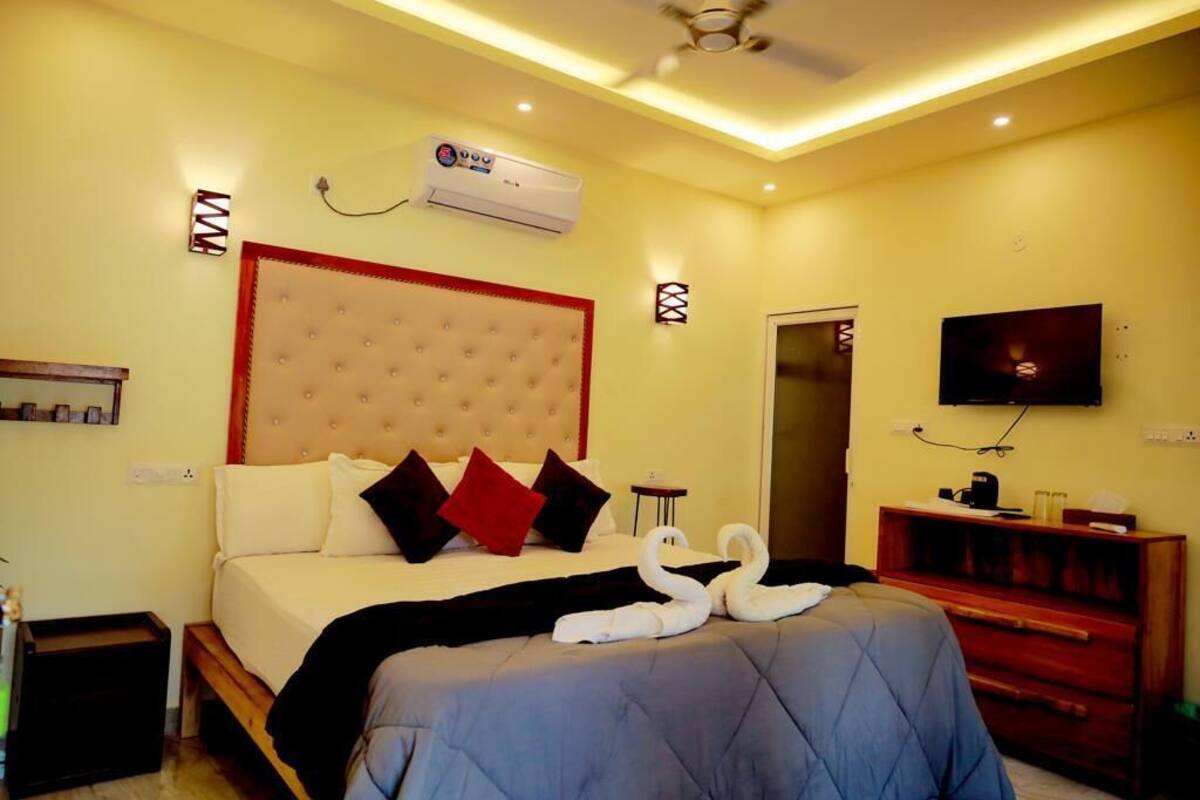 Una habitación de hotel con una cama grande, un equipo de aire acondicionado, un televisor y un aparador de madera.