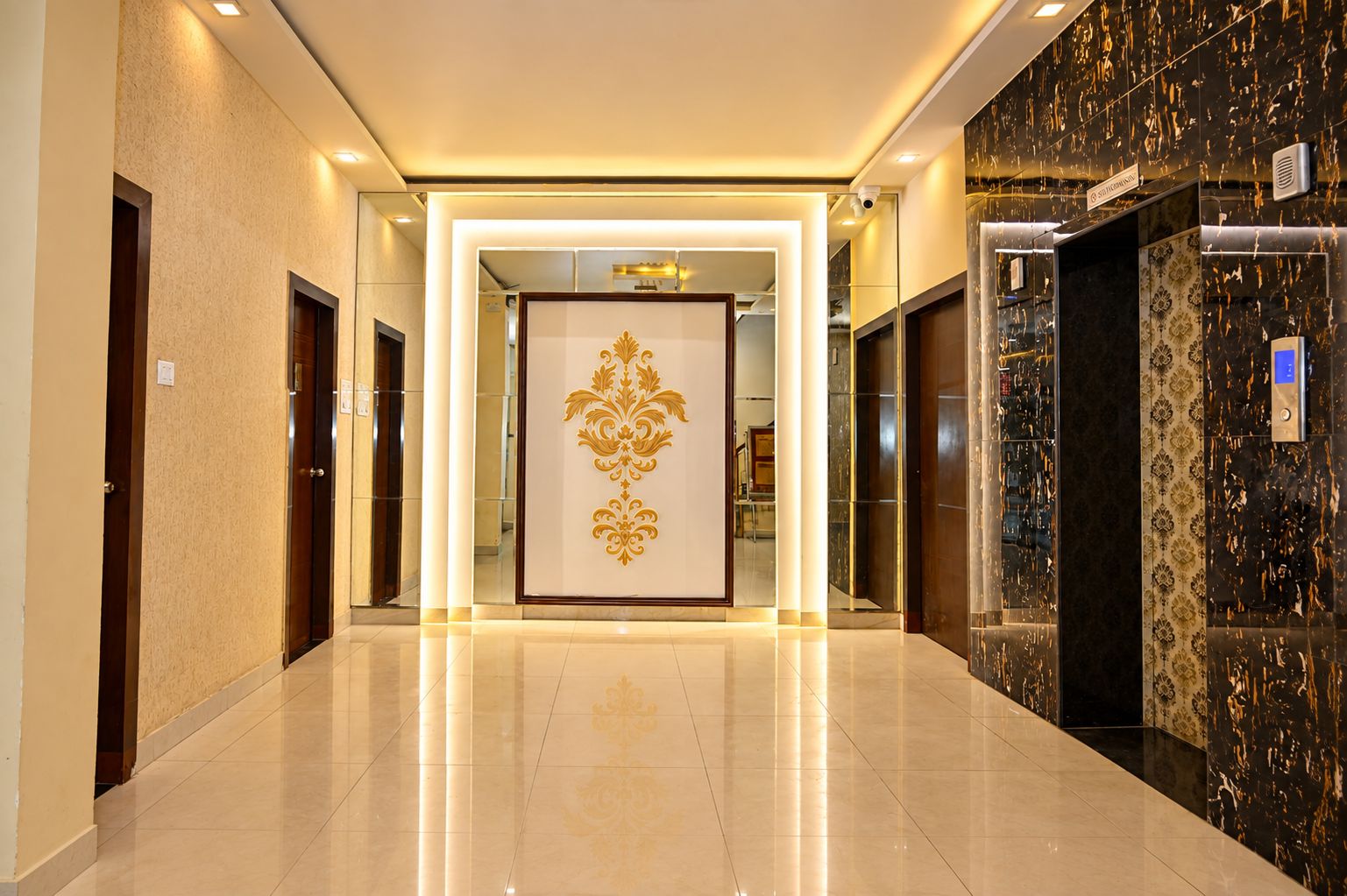 A hotel corridor with a polished floor, a decorative wall panel, and an elevator.