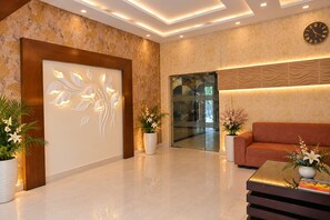 Una hall moderna con reception, divano e piante decorative.
