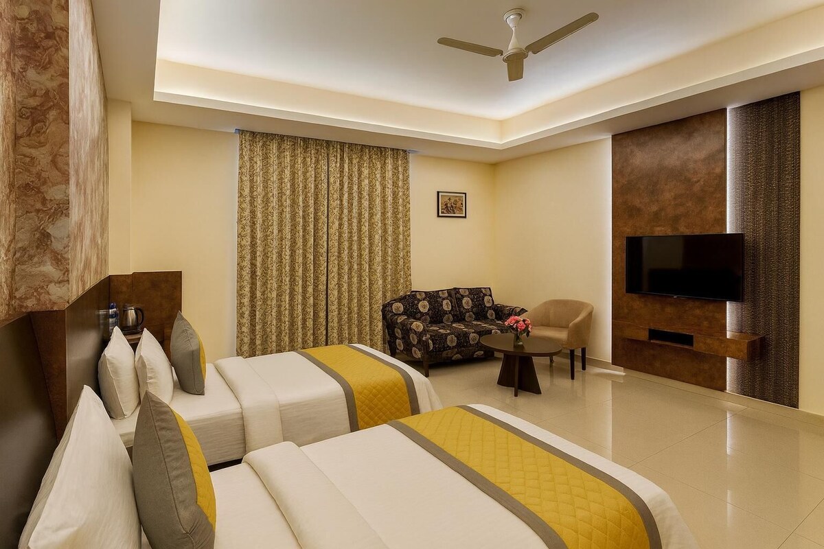 A hotel room with a bed, a sofa, a TV, and a ceiling fan.