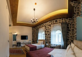 Un dormitorio con dos camas, un escritorio, un televisor y una pared de piedra.