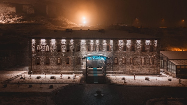Un edificio de piedra histórico con una entrada central, iluminado por luces.
