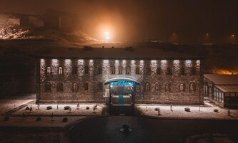Un edificio de piedra histórico con una entrada central, iluminado por luces.