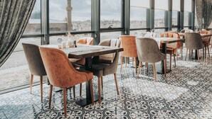 Un restaurante con vistas a un paisaje urbano, que presenta un suelo estampado y muebles modernos.