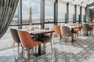 Un restaurante con vistas a un paisaje urbano, que presenta un suelo estampado y muebles modernos.