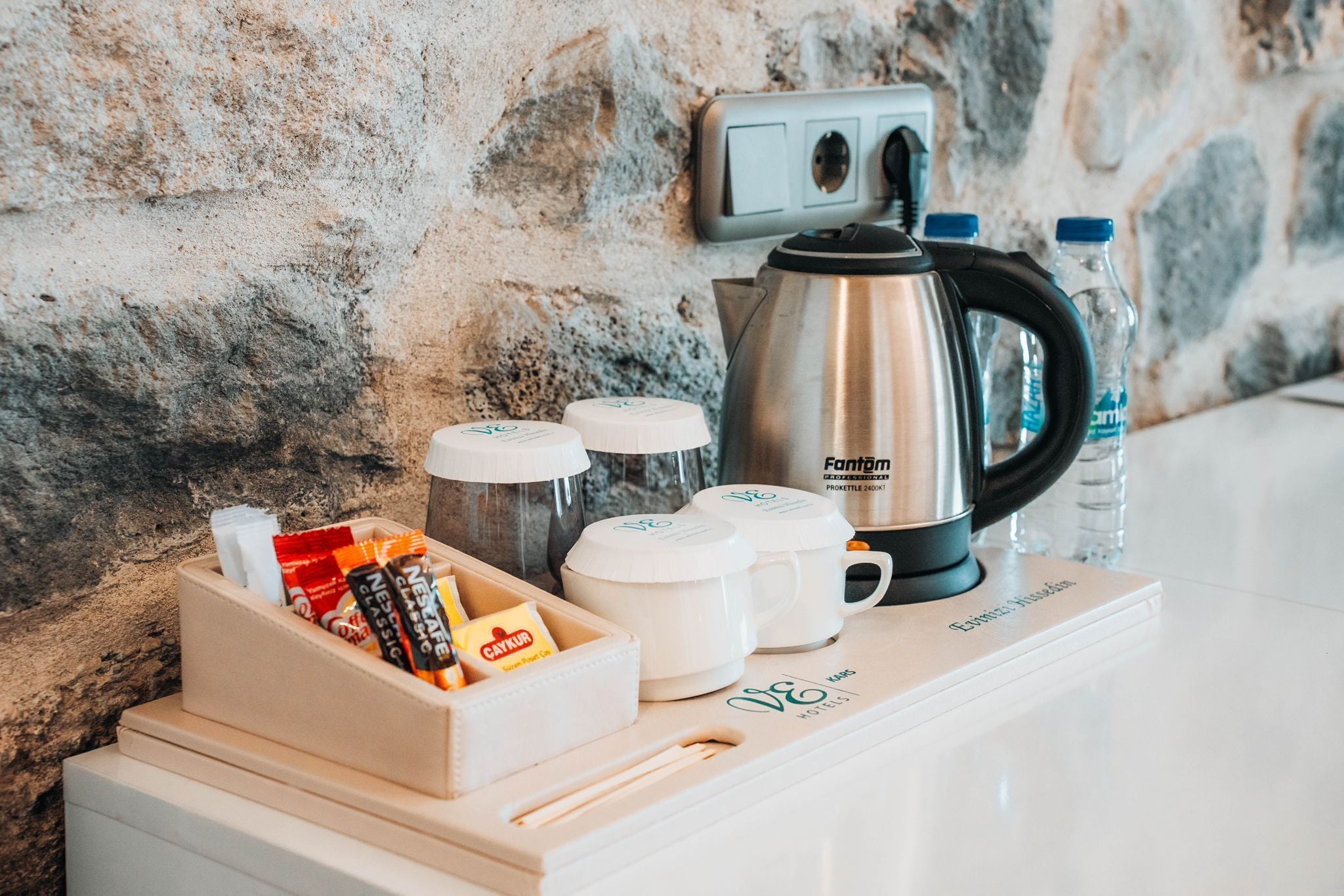 A kitchenette with a coffee maker, water bottles, and coffee pods.