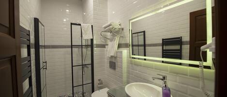 Une salle de bain moderne avec une douche à parois de verre, des toilettes blanches et un meuble-lavabo doté d’un grand miroir.