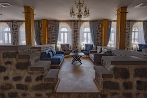 Una habitación amplia con paredes de piedra, un banco de madera y una mesa en el centro.