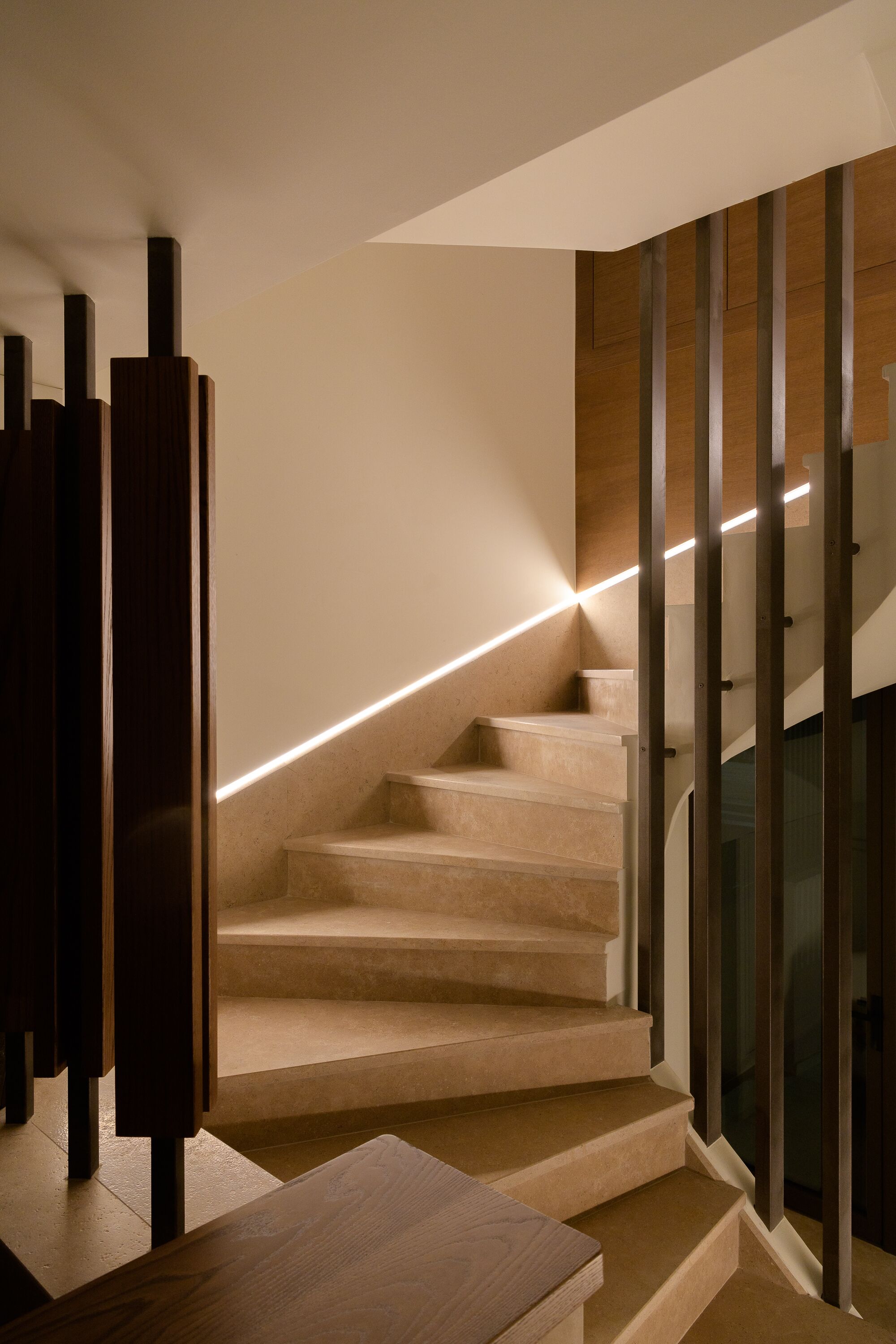 A modern staircase with a wooden finish, glass railings, and a light strip along the edge.