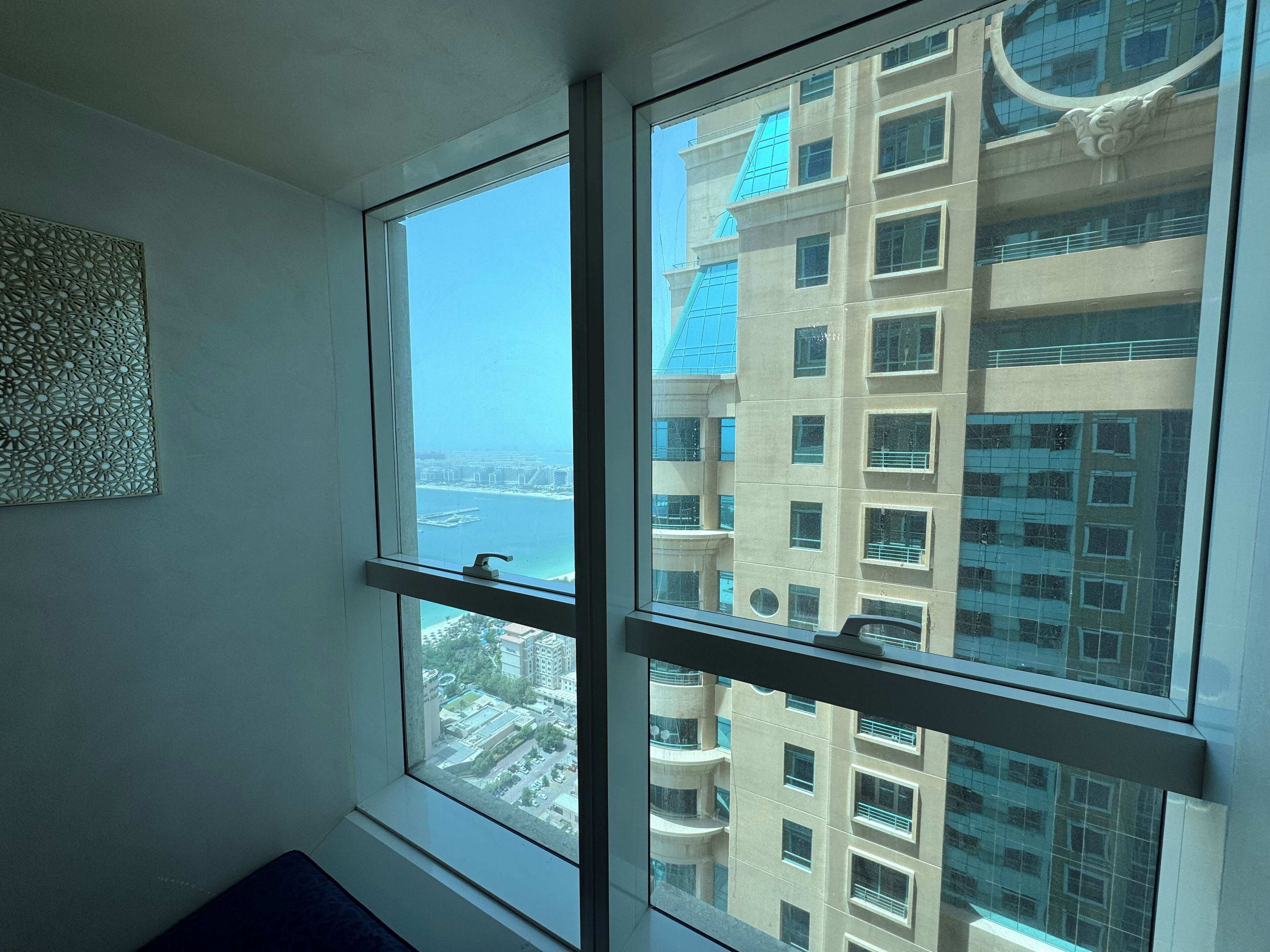 A room with a large window overlooking a high-rise building and a body of water.