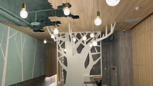 A modern office space with a wooden ceiling, a tree-shaped partition, and multiple hanging light bulbs. - SHINSHIN HOTEL (Taipei)