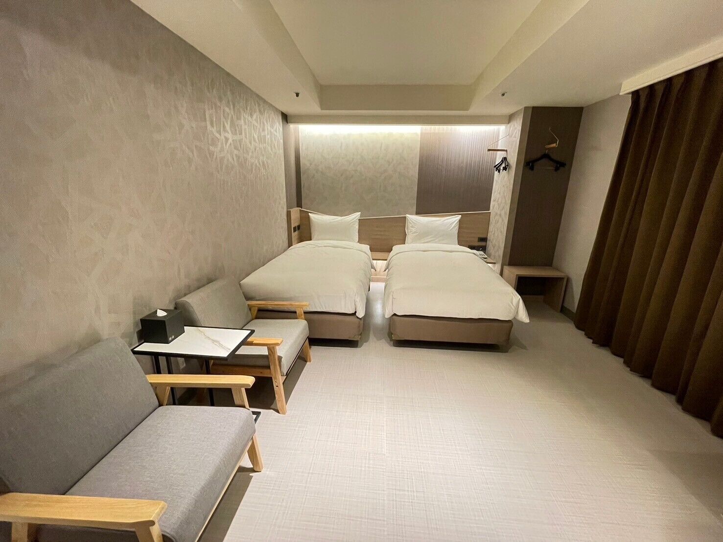 Une chambre d’hôtel avec deux lits, un bureau et une chaise.