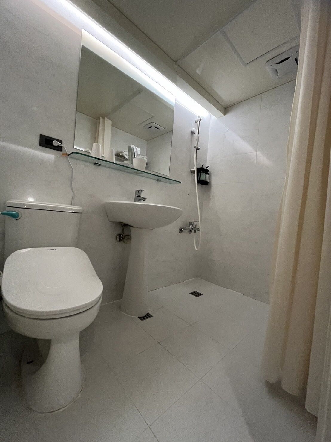 A bathroom with a toilet, sink, and shower.