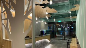 A modern interior with a reception desk, seating area, and a tree-like decorative partition. - SHINSHIN HOTEL (Taipei)