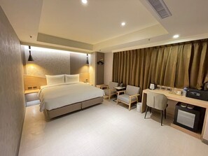 A modern hotel room with a bed, desk, chair, and a small kitchenette. - SHINSHIN HOTEL (Taipei)