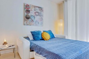 A bedroom with a bed, a bedside table, a lamp, and a wall art piece. - Beachfront Haven: Pools, Direct Ocean Access (Hollywood)