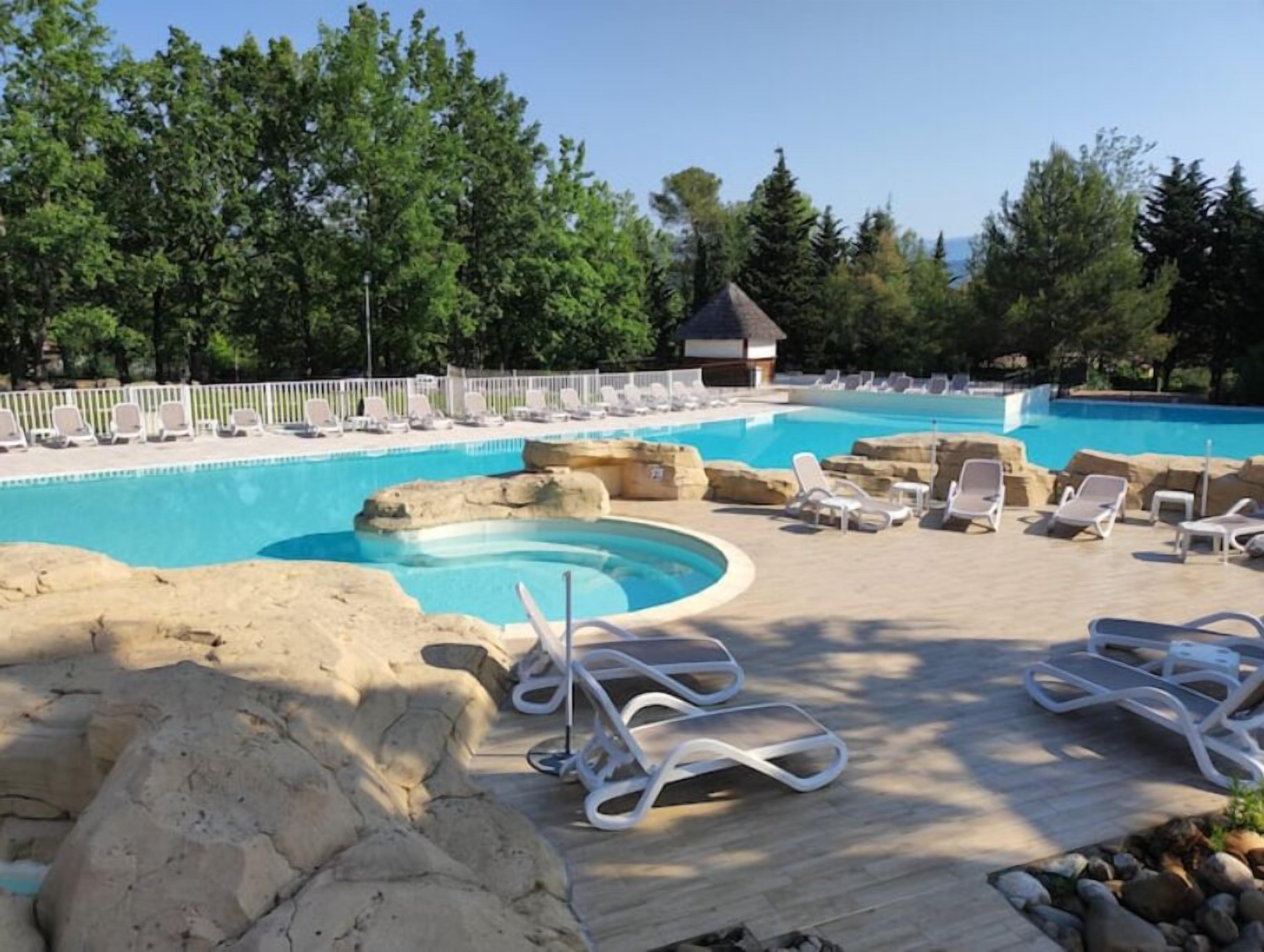 A pool area with lounge chairs, a small hut, and a wooden deck.