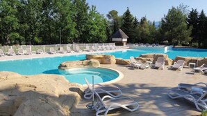 A pool area with lounge chairs, a small hut, and a wooden deck.
