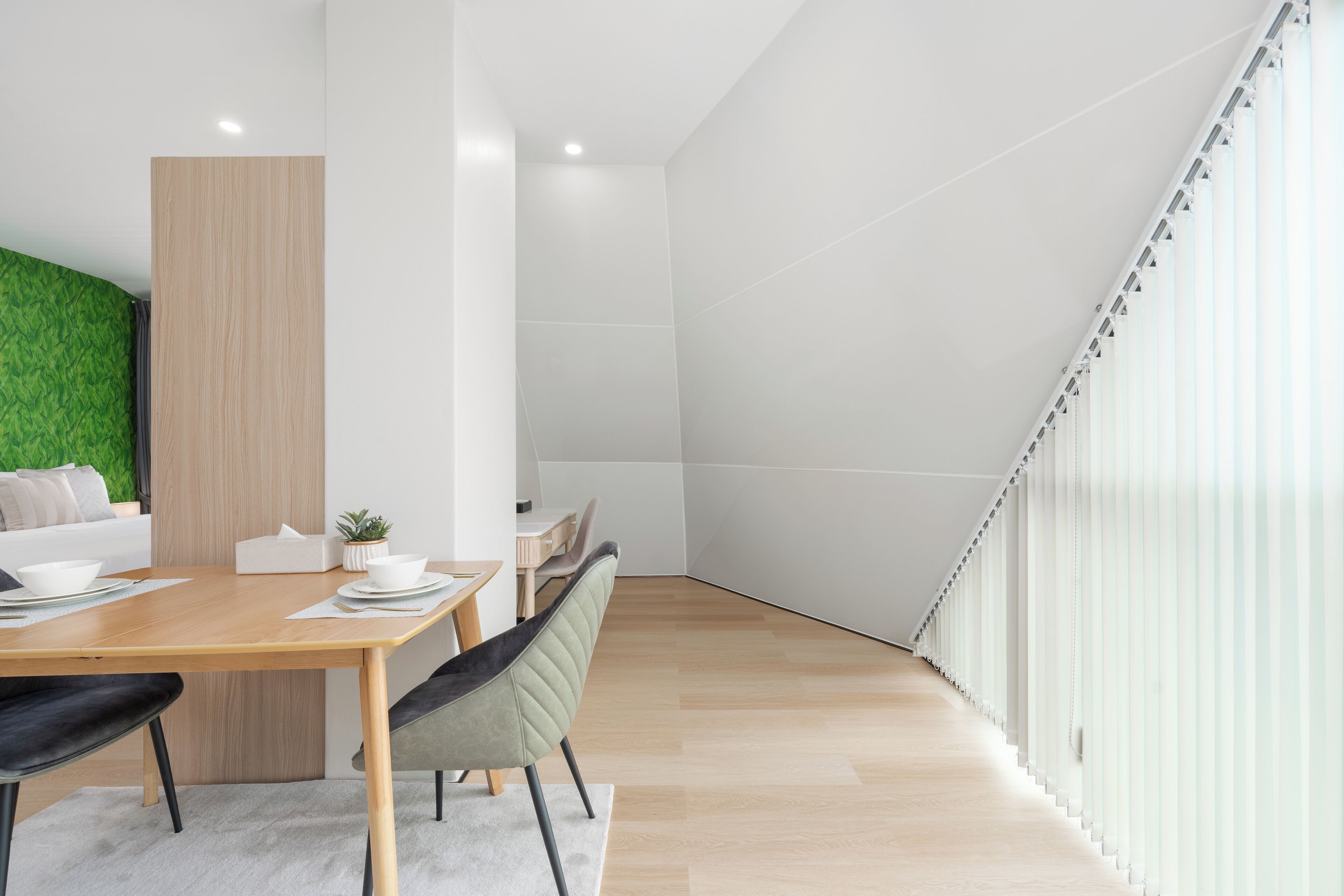 A modern dining area with a wooden table, chairs, and a green accent wall.