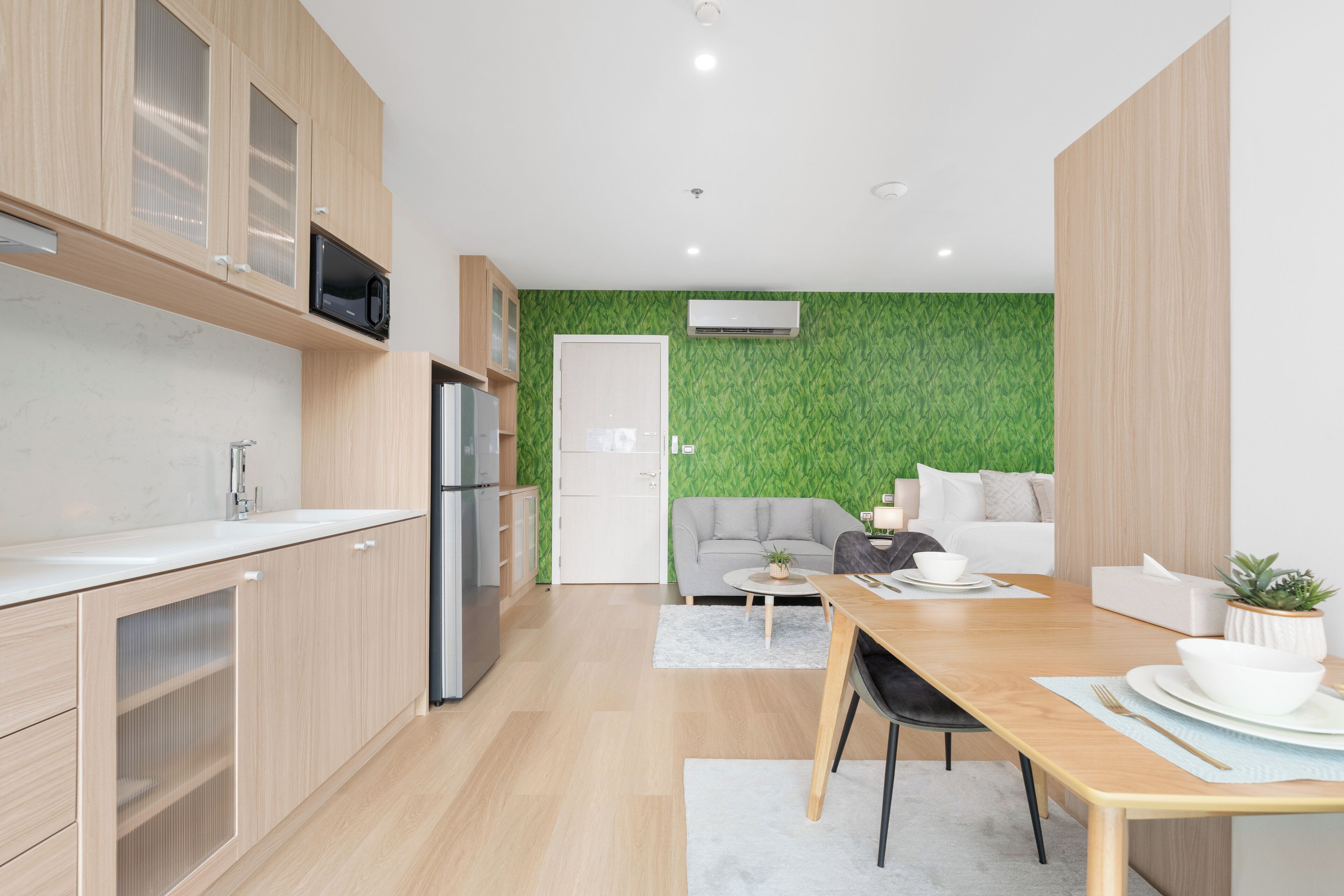 A modern kitchen with wooden cabinets, a built-in microwave, and a stainless steel refrigerator.