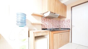 Une cuisine avec des meubles de rangement en bois, un pare-feu en carreaux et un distributeur d’eau.