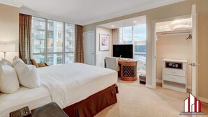 A hotel room with a large bed, a desk with a chair, a TV, and a closet.