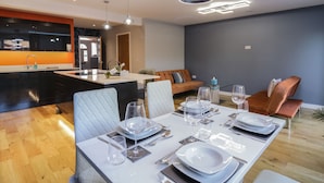 A modern dining area with a white table set for four, surrounded by cushioned chairs. - Magnolia House (Reading)