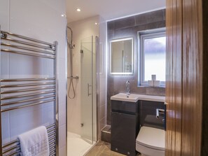 Un baño moderno con cabina de ducha de vidrio, tocador con espejo y retrete.