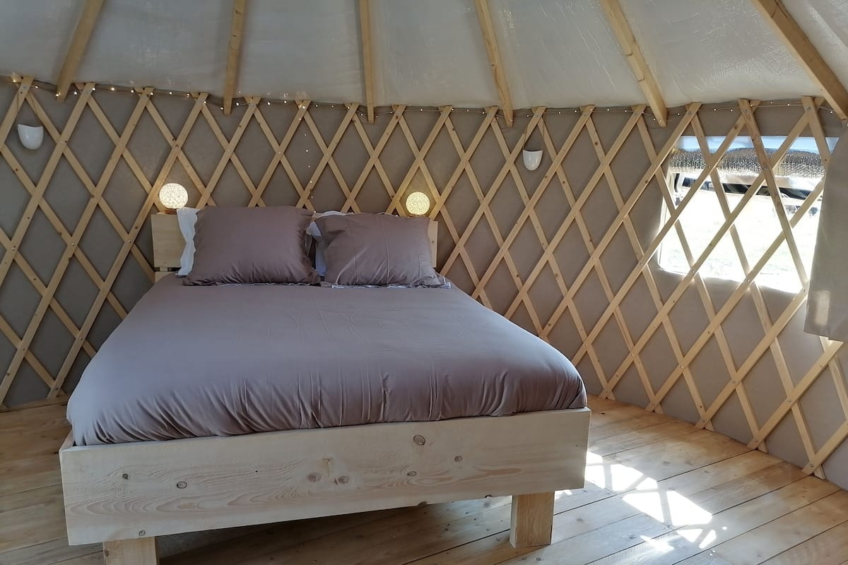 A bed in a wooden room with a lattice wall and string lights.