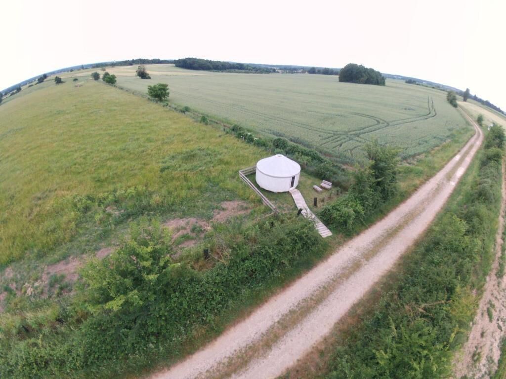 A large, white, cylindrical structure in a rural setting with a dirt road leading to it.
