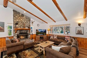 Una sala de estar acogedora con chimenea de piedra, vigas de madera y un ventanal grande.