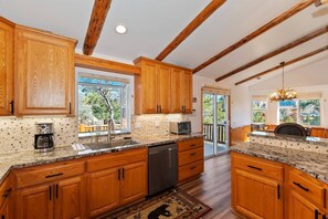 A kitchen with wooden cabinets, granite countertops, and a dishwasher. - Located in the Castle Glen Estates! Recently Remodeled Master! Pet Friendly! Pool Table! Foosball! (Big Bear Lake)
