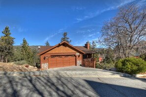 A single-story house with a garage, surrounded by trees and a clear sky.